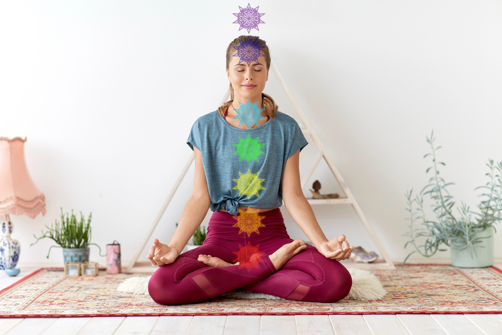 woman meditating in lotus pose with colorful chakra symbols aligned along the body, representing reiki & chakras healing and energy balance