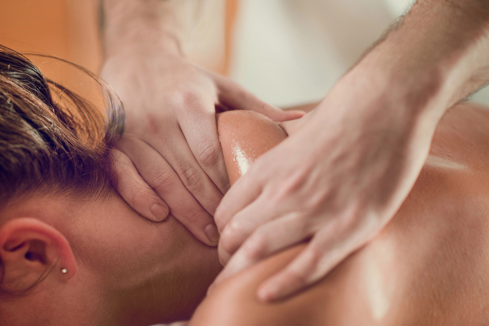 close-up of a massage therapist working on a client's neck and shoulder muscles with targeted pressure to reduce stiffness, relieve pain, and improve range of motion