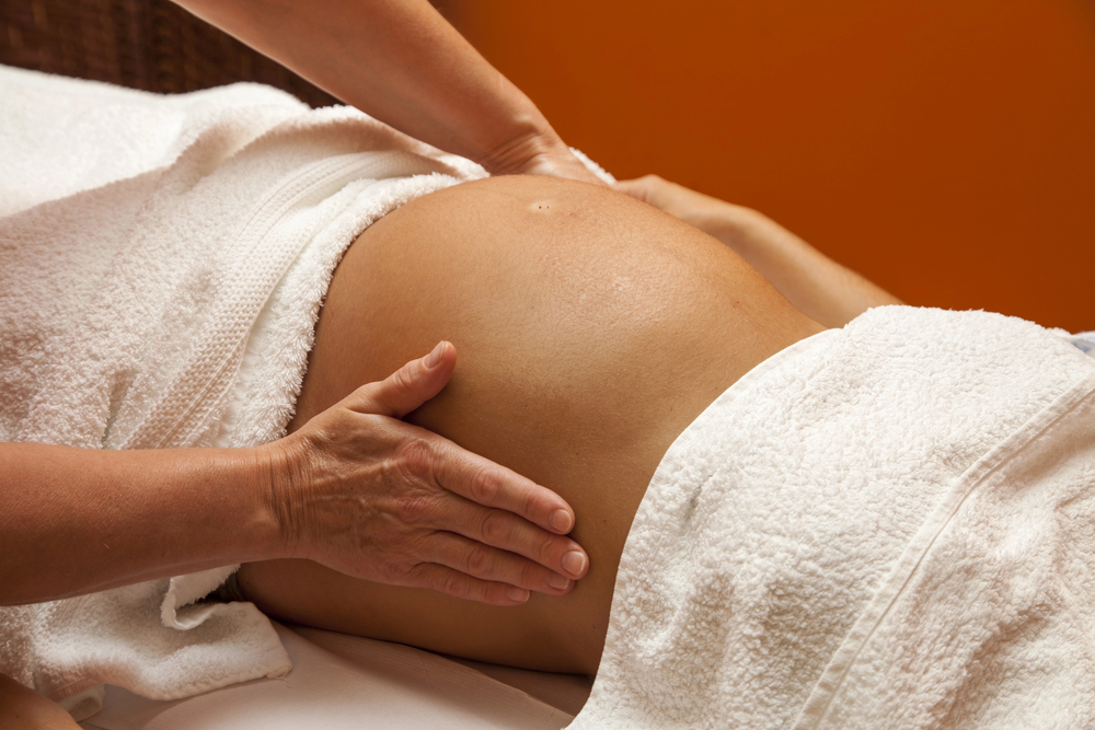 massage therapist massaging pregnant person's stomach